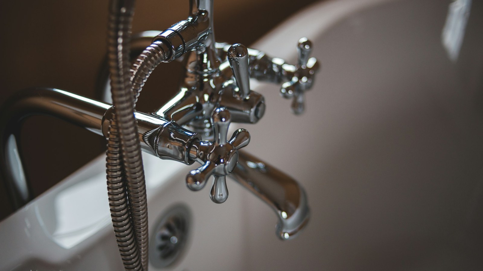 Chrome bathtub faucet and shower hose on a white tub, illustrating residential plumbing fixtures related to repair cost planning in Leesburg, VA